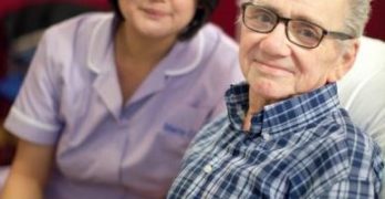Man in pyjamas with a nurse, both smiling