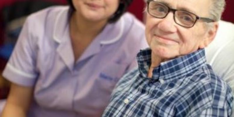 Man in pyjamas with a nurse, both smiling