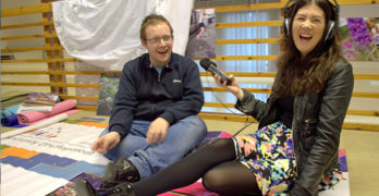 Person, smiling, holding microphone to interview
