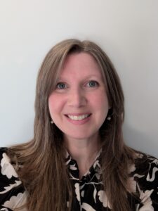 A portrait picture of Sarah Latto smiling and wearing a black and white top. 